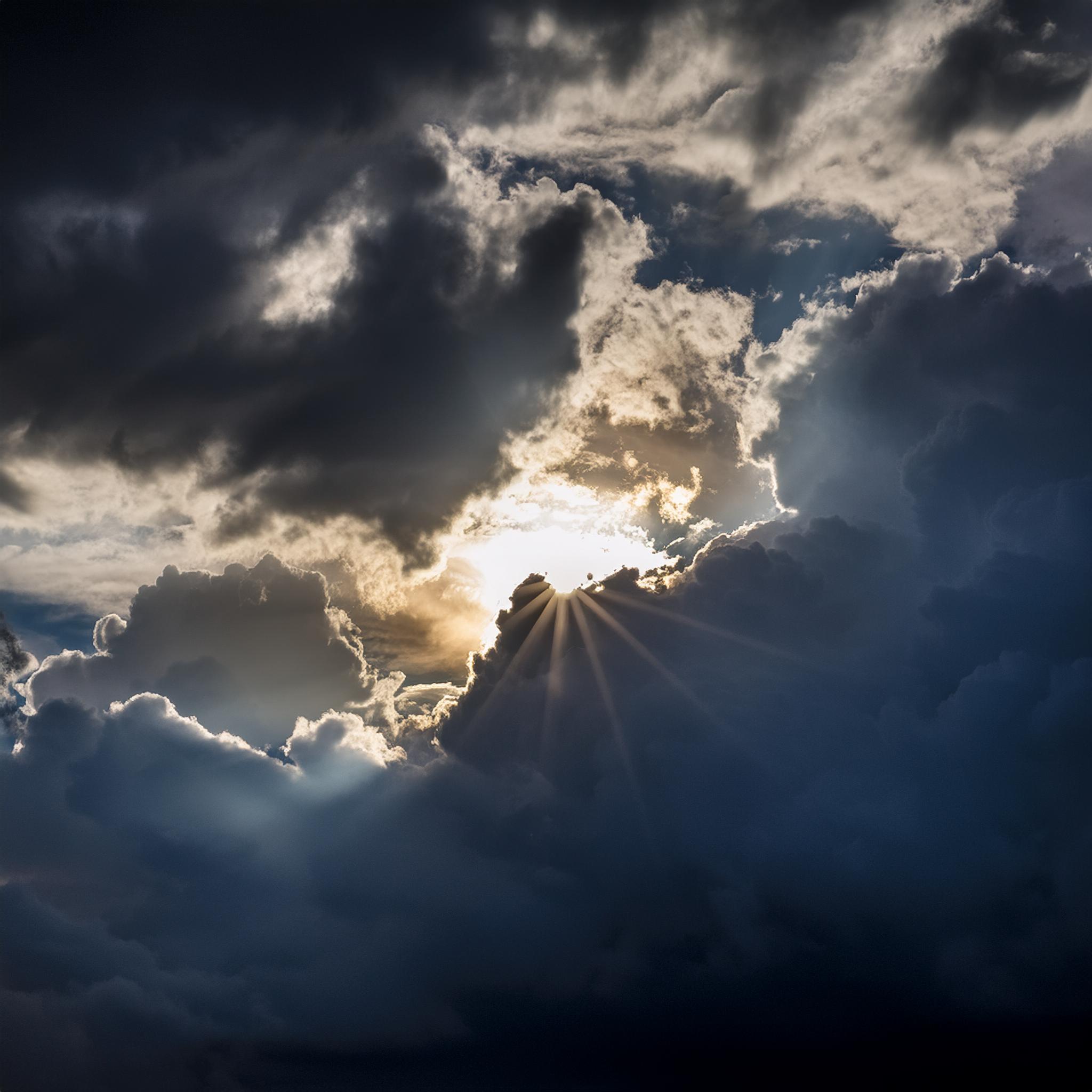 the sun peeking out from between dark clouds